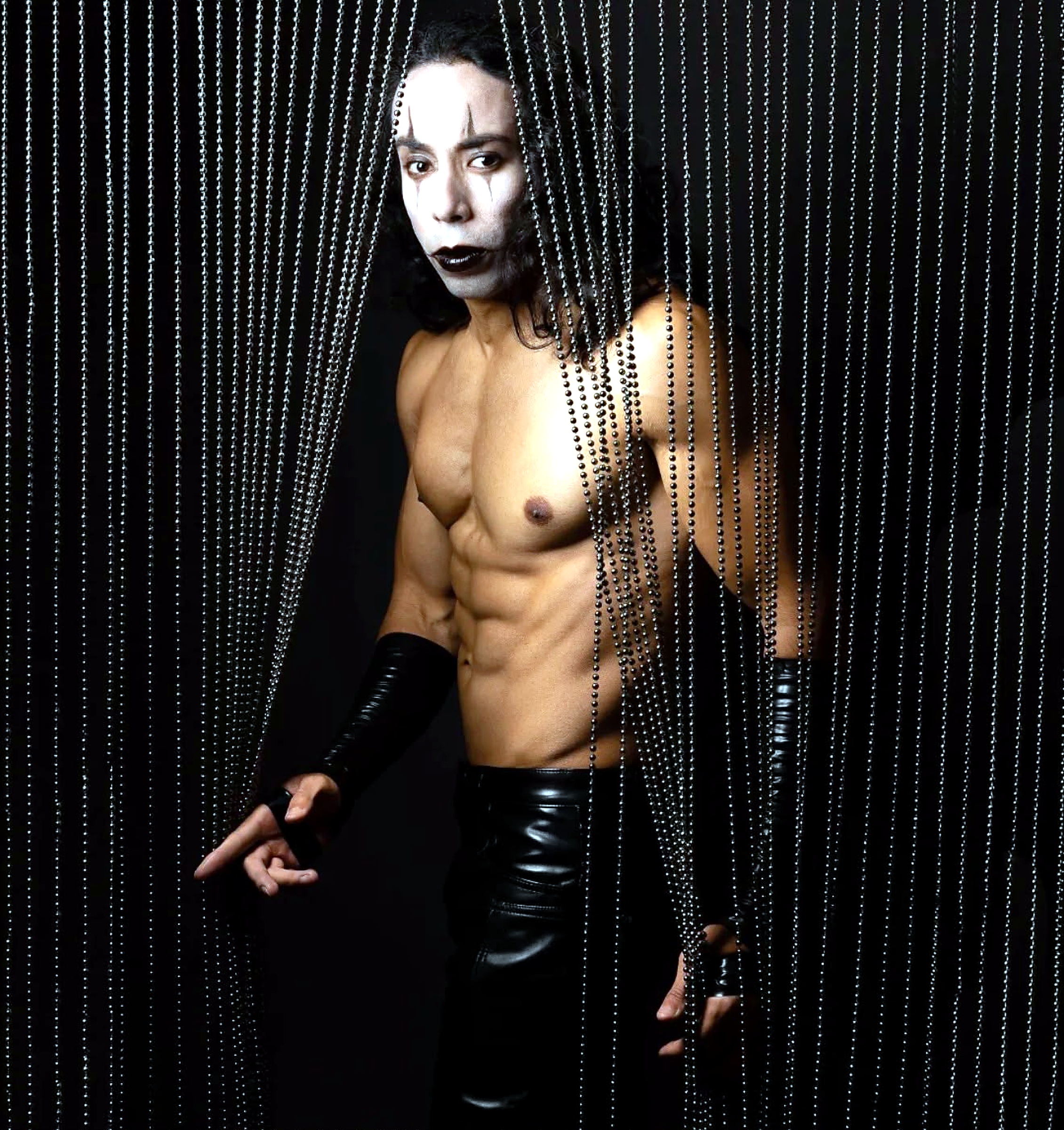 Damien behind metallic bead curtains in theatrical makeup