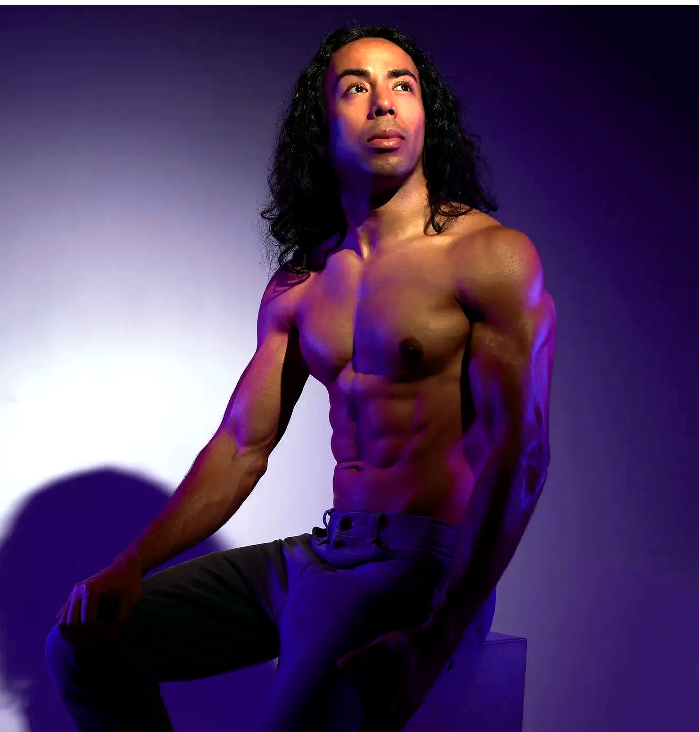 Damien seated in violet stage light